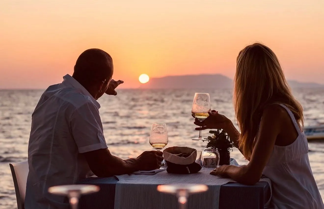 A table for two set at the water's edge as the sun goes down