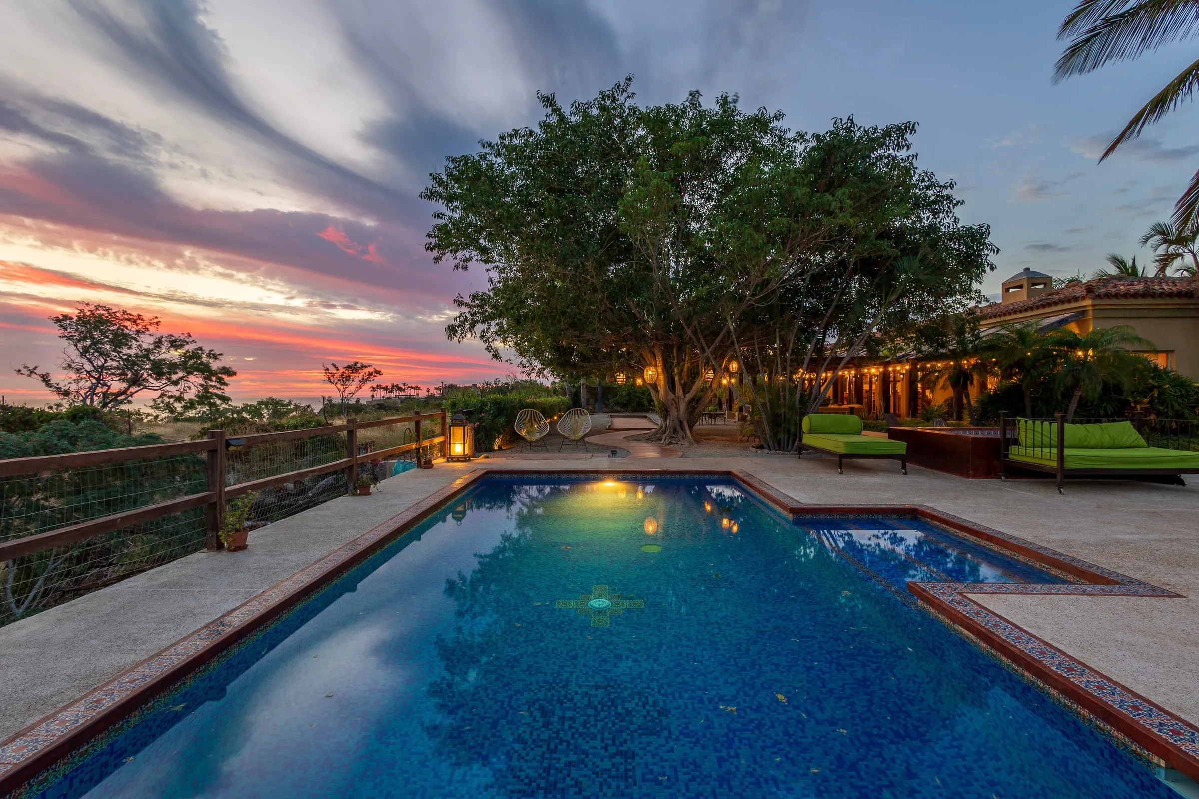 The lit pool at dusk with the garden and the sky behind it
